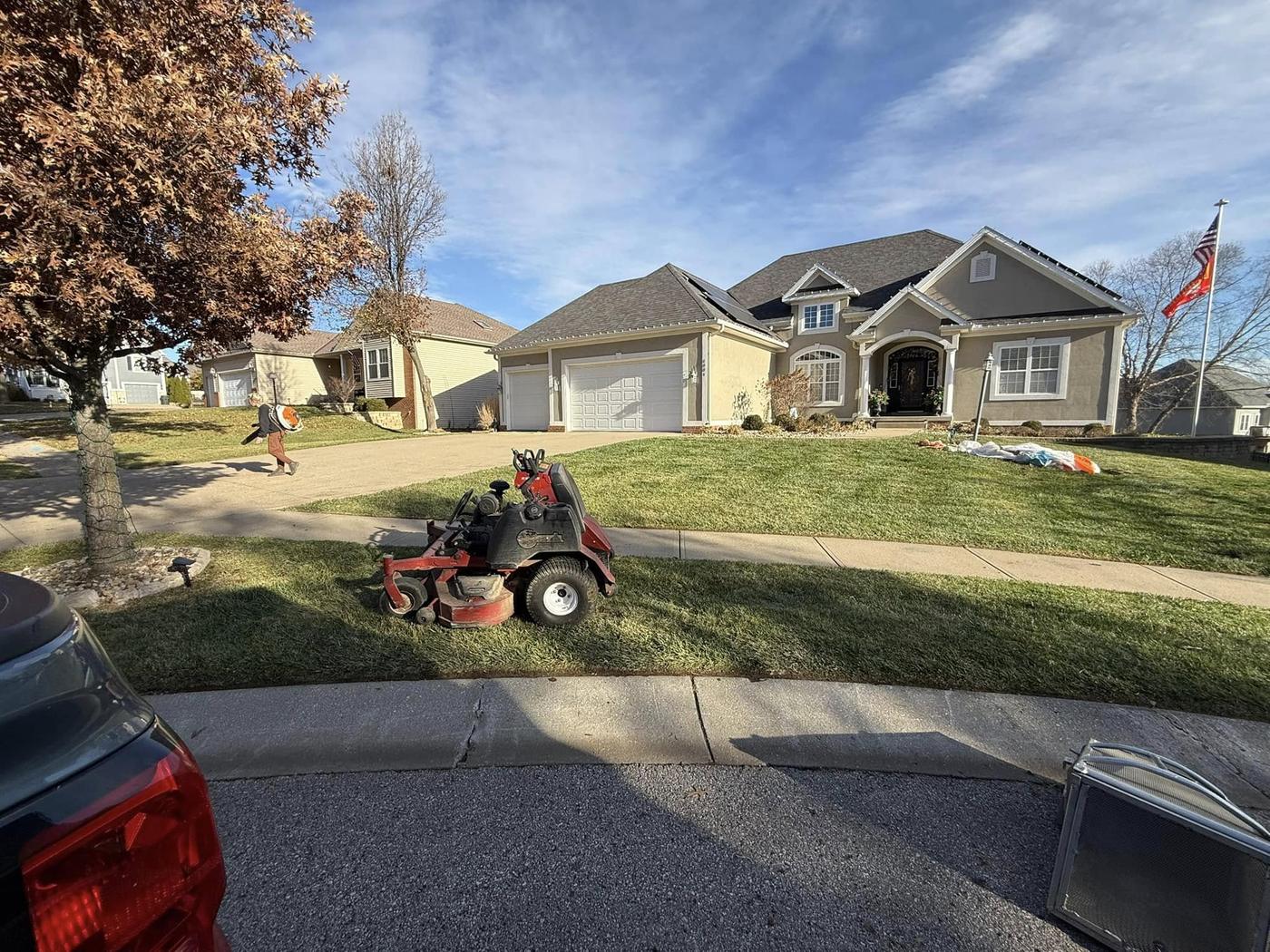 A zero-turn mower parked on a suburban front lawn